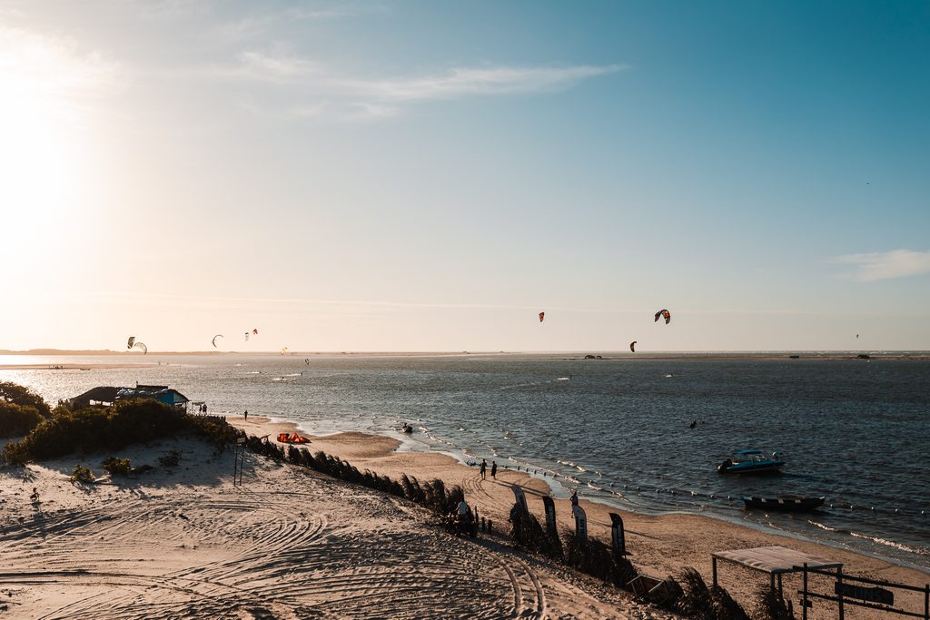 Vista panorâmica do pôr do sol na praia de Atins com kitesurfistas ao fundo, Lençóis Maranhenses.