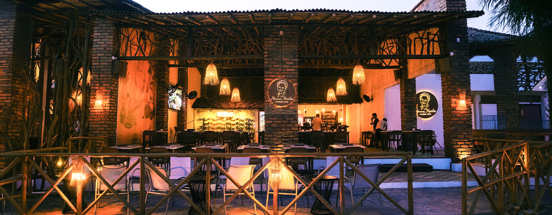 Entrada nocturna al restaurante Nonna Marta en Atins, Maranhão, con iluminación cálida y estilo arquitectónico local, parte de Charme Atins.