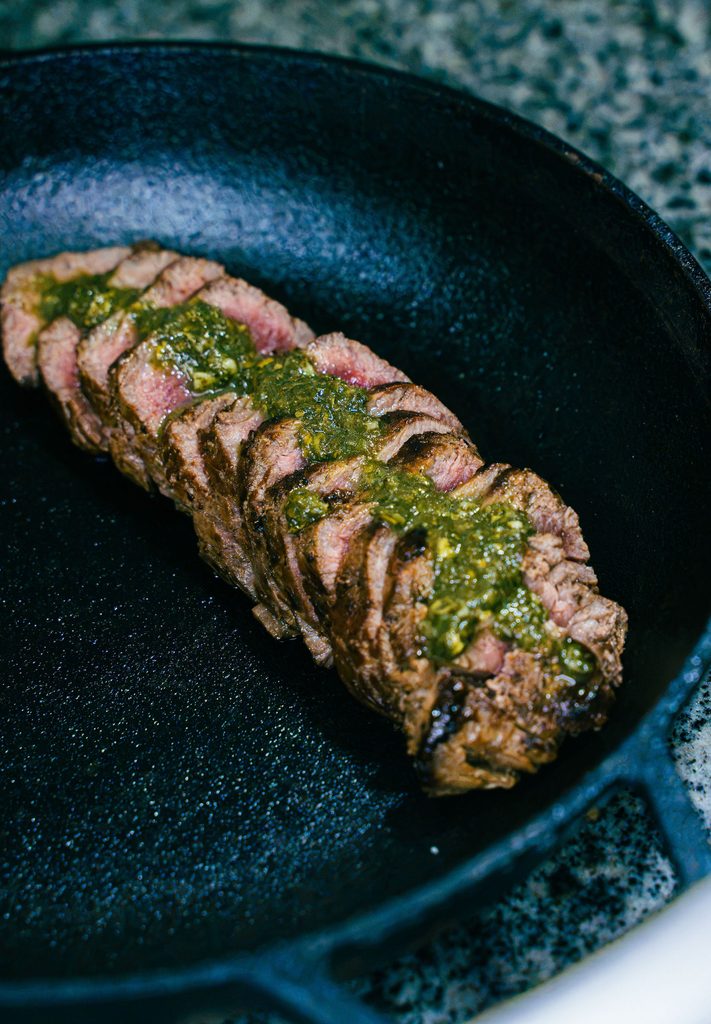 Corte de carne grelhada fatiada com molho chimichurri em frigideira de ferro no Restaurante Nonna Marta em Atins.