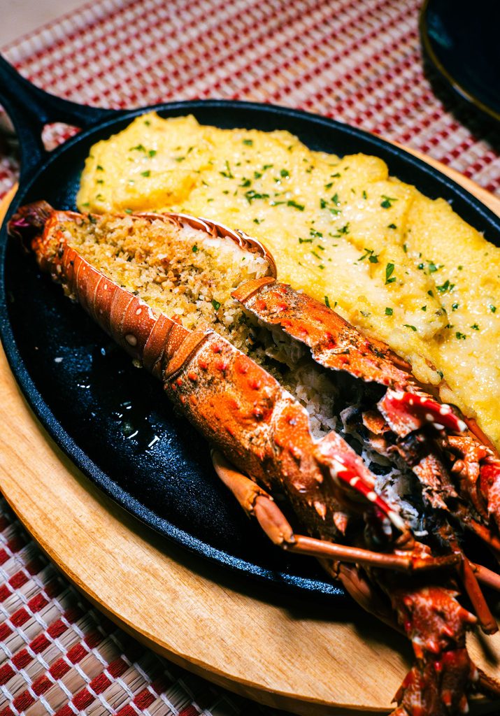 Lagosta recheada e grelhada servida com acompanhamento cremoso em frigideira de ferro no Restaurante Nonna Marta em Atins.