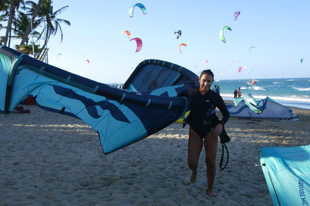 Kitesurfista sorrindo e carregando equipamento na praia de Atins.