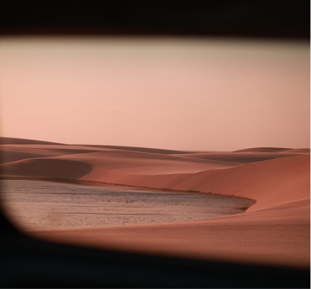 Paisagem das dunas e lagoa nos Lençóis Maranhenses durante o pôr do sol.