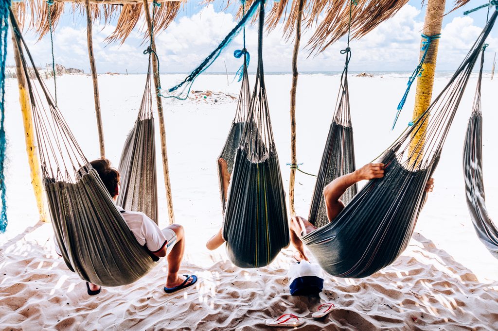 Pessoas relaxando em redes cobertas de palha na praia em Atins.